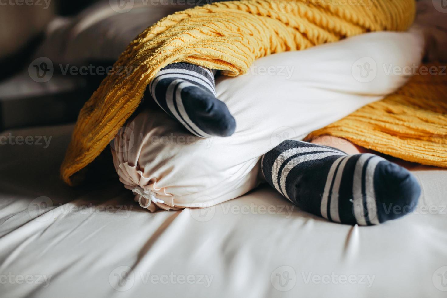 le persone dormono sotto le coperte e abbracciano i cuscini in calzini caldi foto