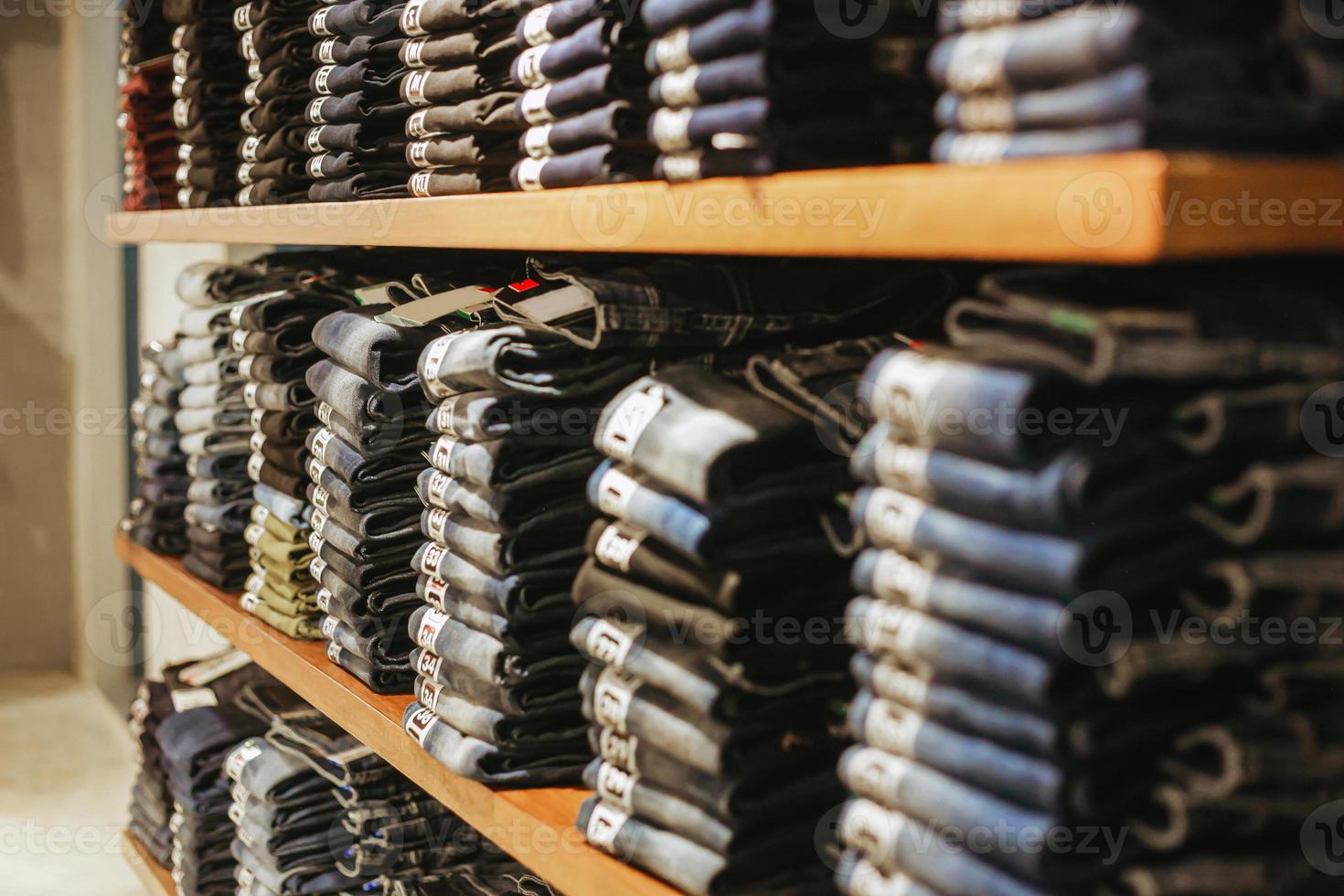 mucchio di pantaloni in denim sul display rack del negozio foto