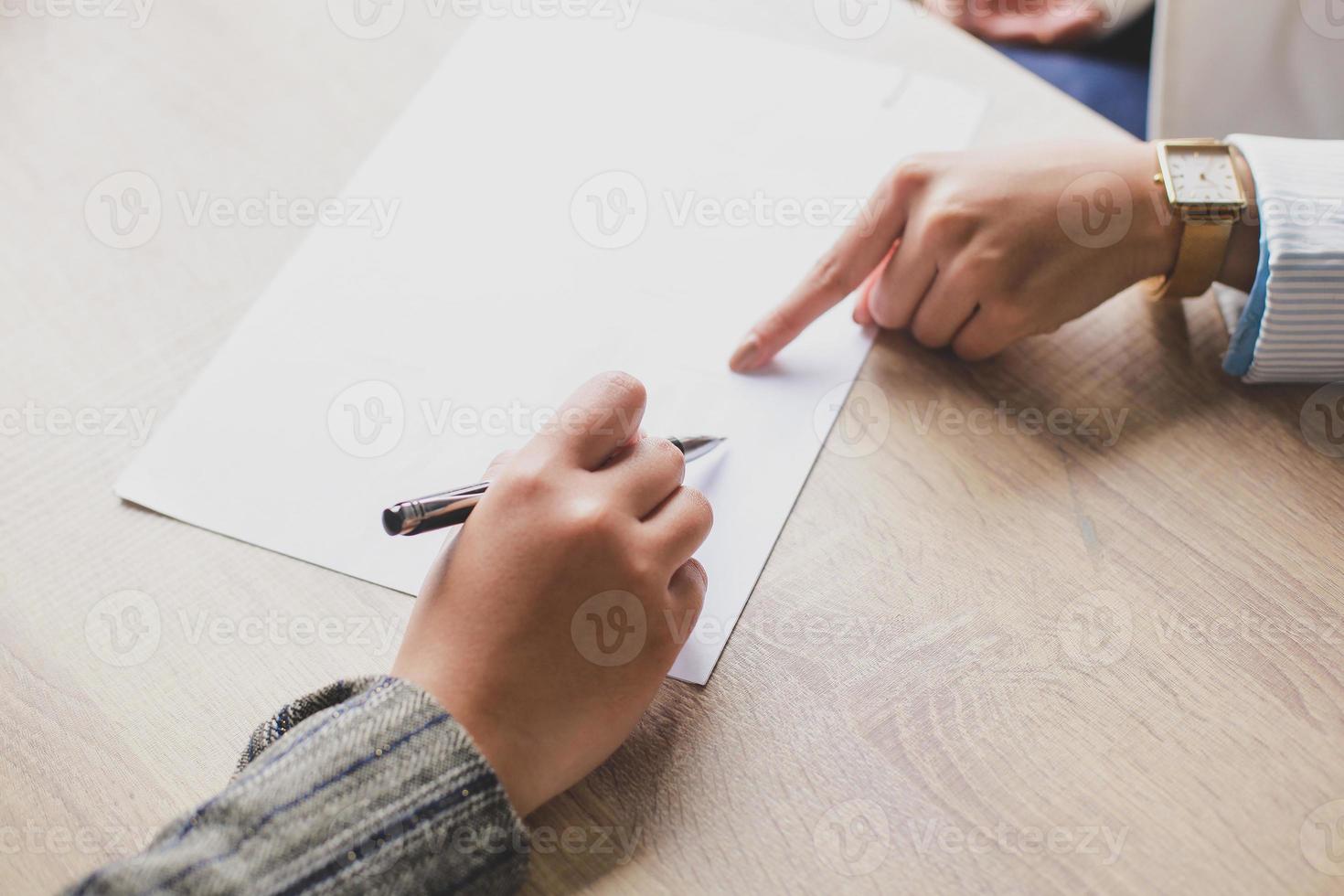 mano di due donne su carta bianca nella scrivania in ufficio, fare un affare, firmare un accordo, spazio libero, spazio per la copia, posto per il testo. foto