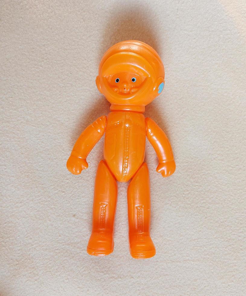 astronauta in uno sfondo di tuta spaziale arancione di un plaid beige. giocattolo di plastica retrò. spazio. foto