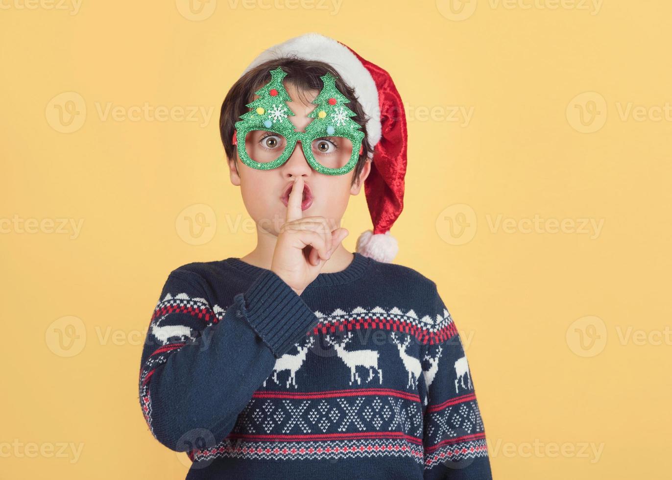 bambino che indossa il cappello di Babbo Natale che chiede silenzio foto