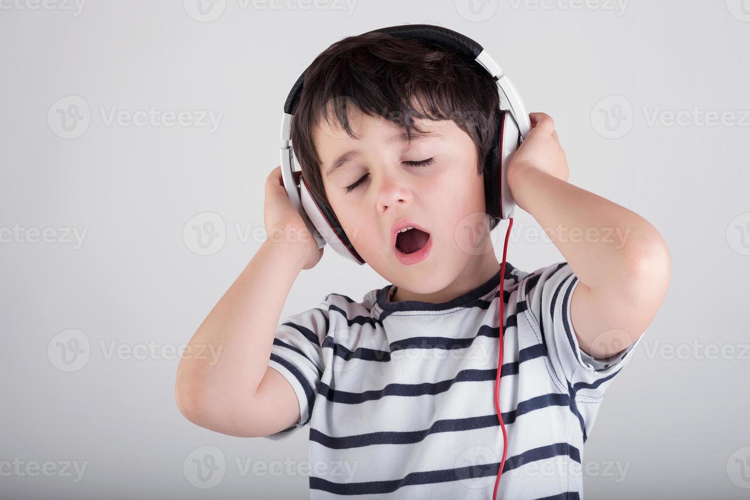 bambino che ascolta la musica con le cuffie foto