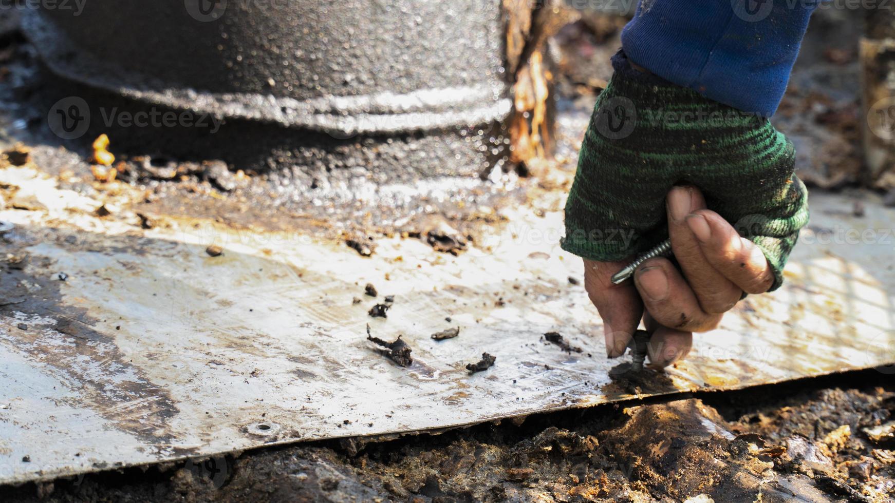 lavoratore che utilizza viti a mano per riparare il tetto in metallo foto