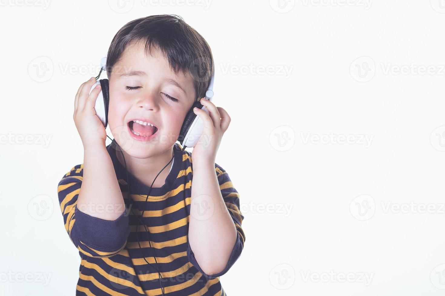 bambino che ascolta la musica con le cuffie foto