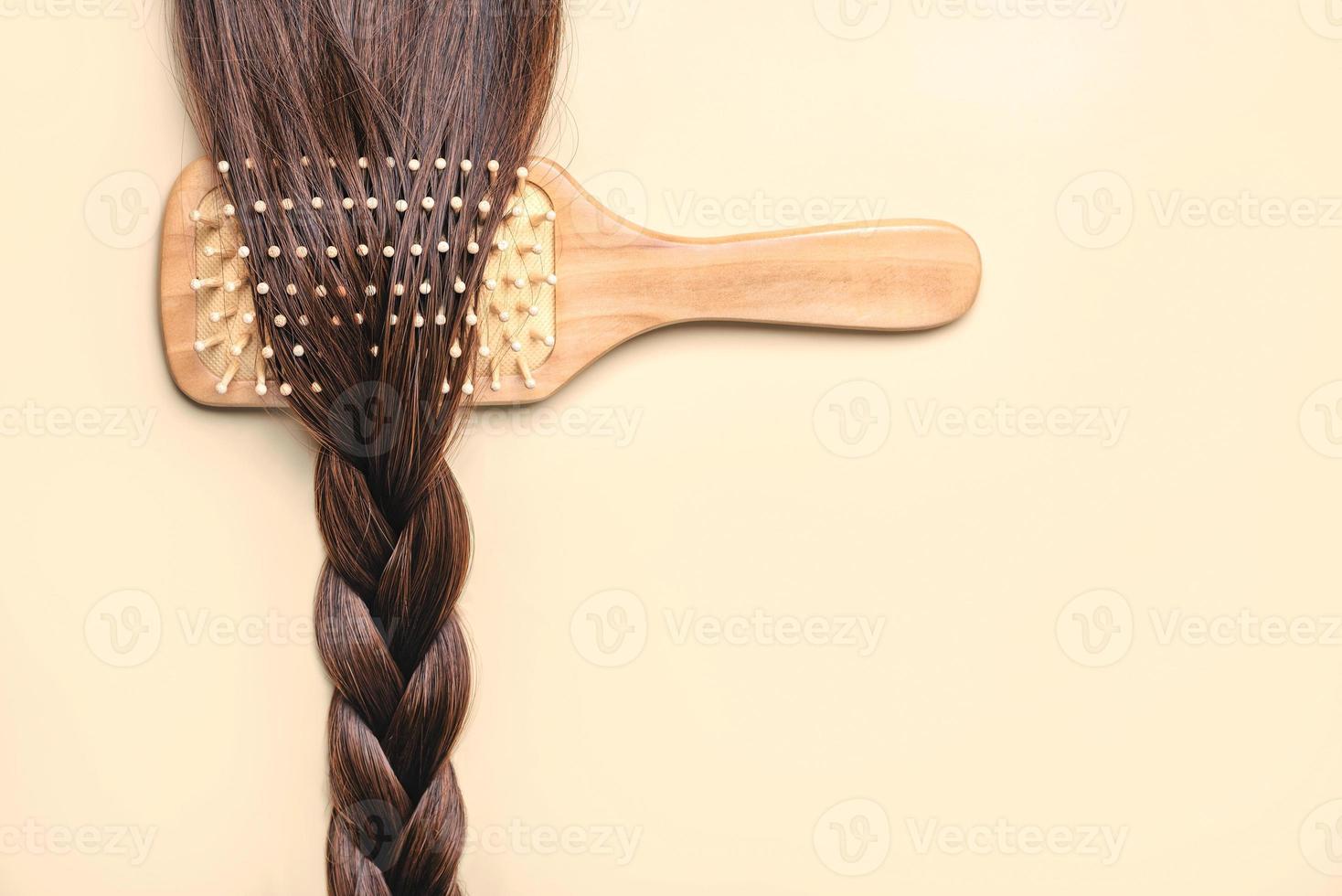 spazzola per capelli con treccia di capelli castani femminili. concetto di parrucchiere e acconciature foto