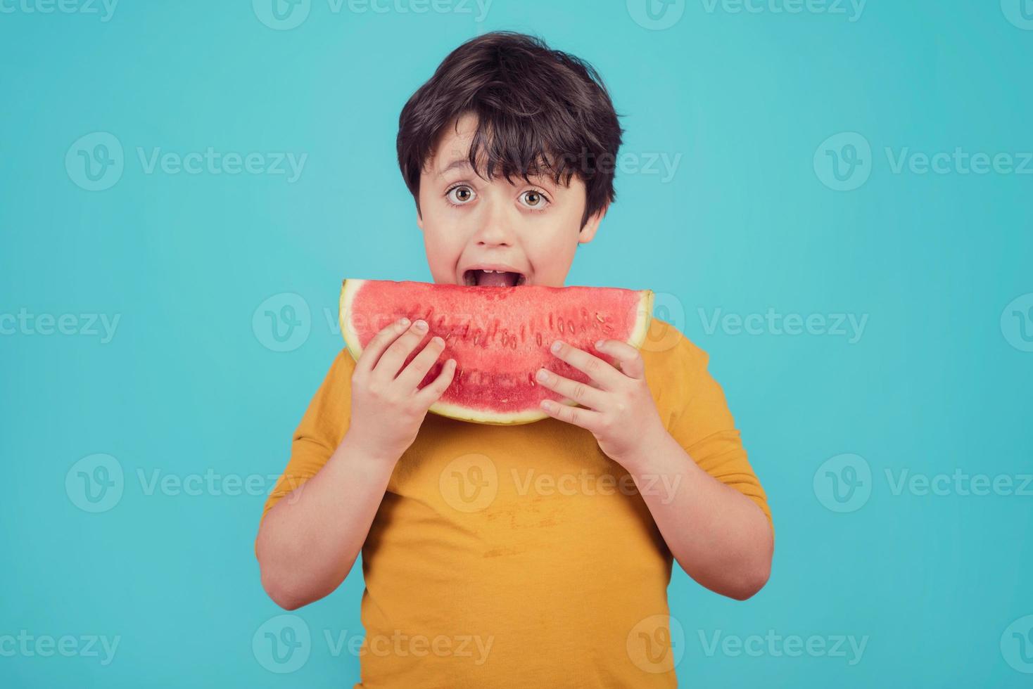 il bambino felice mangia l'anguria foto