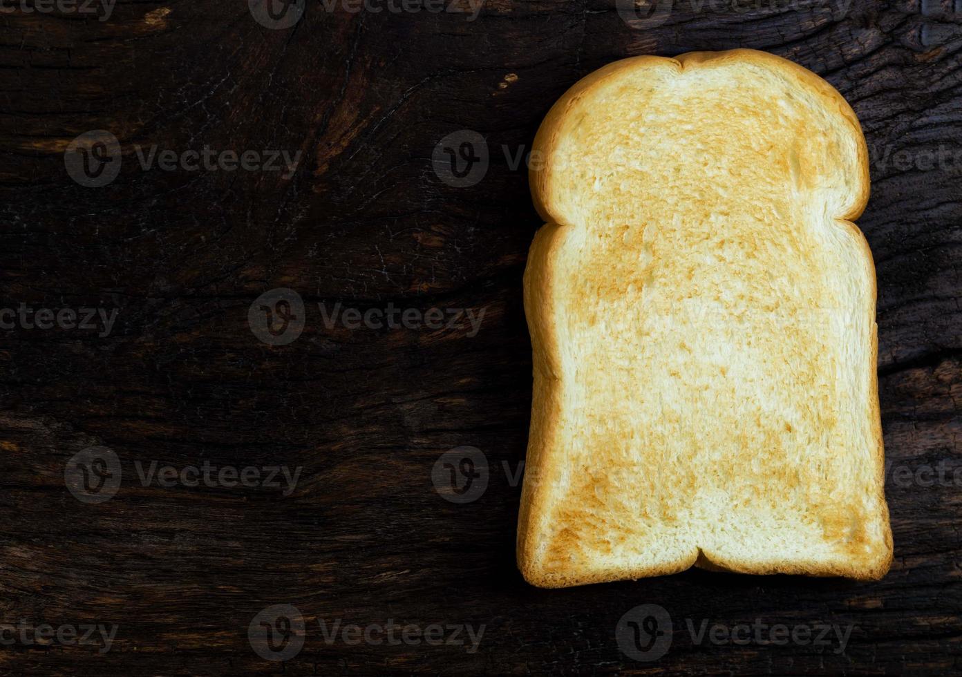 fetta di pane tostato isolata su fondo di legno foto