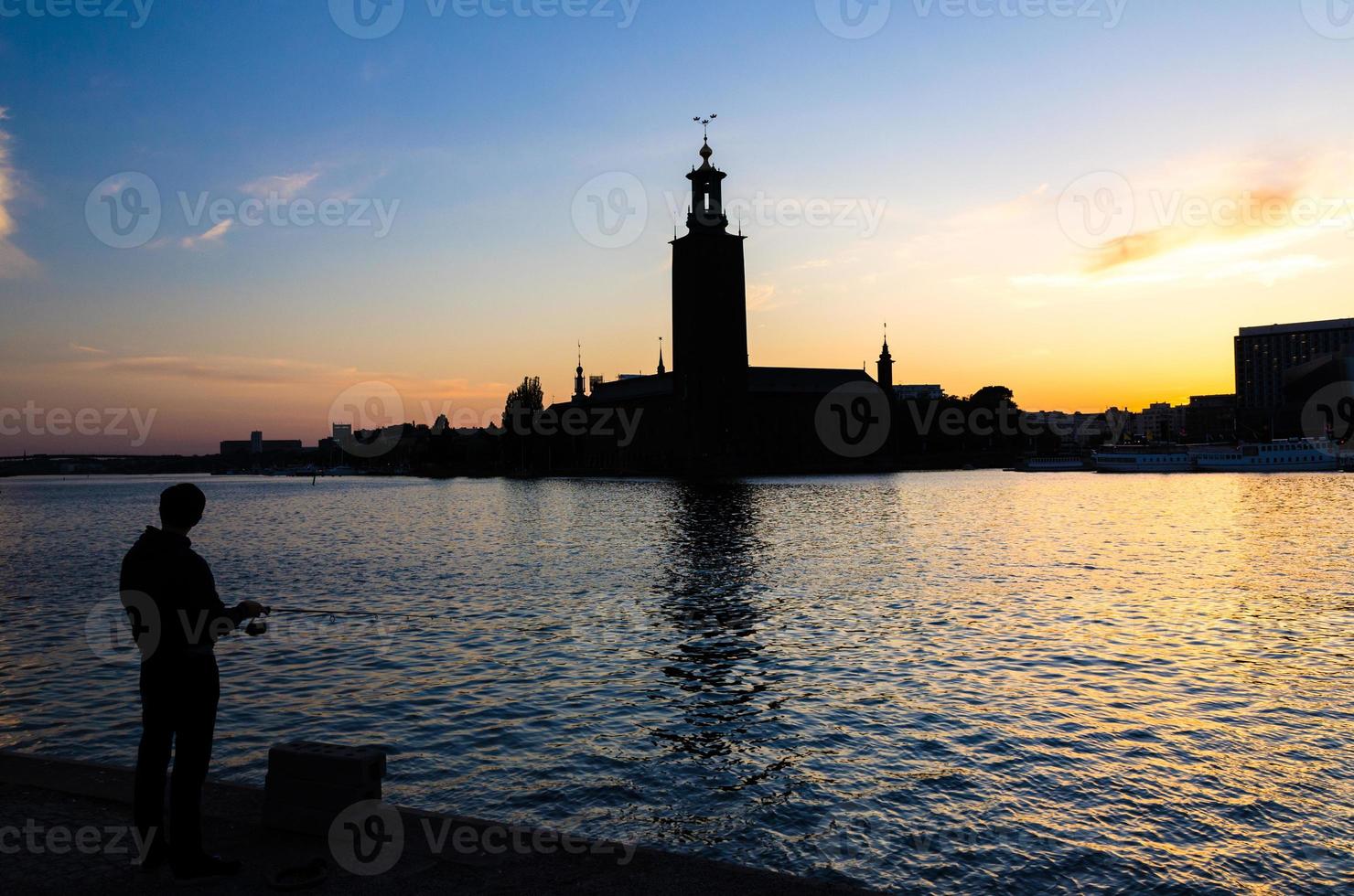 silhouette di pescatore con palo e municipio di stoccolma, svezia foto