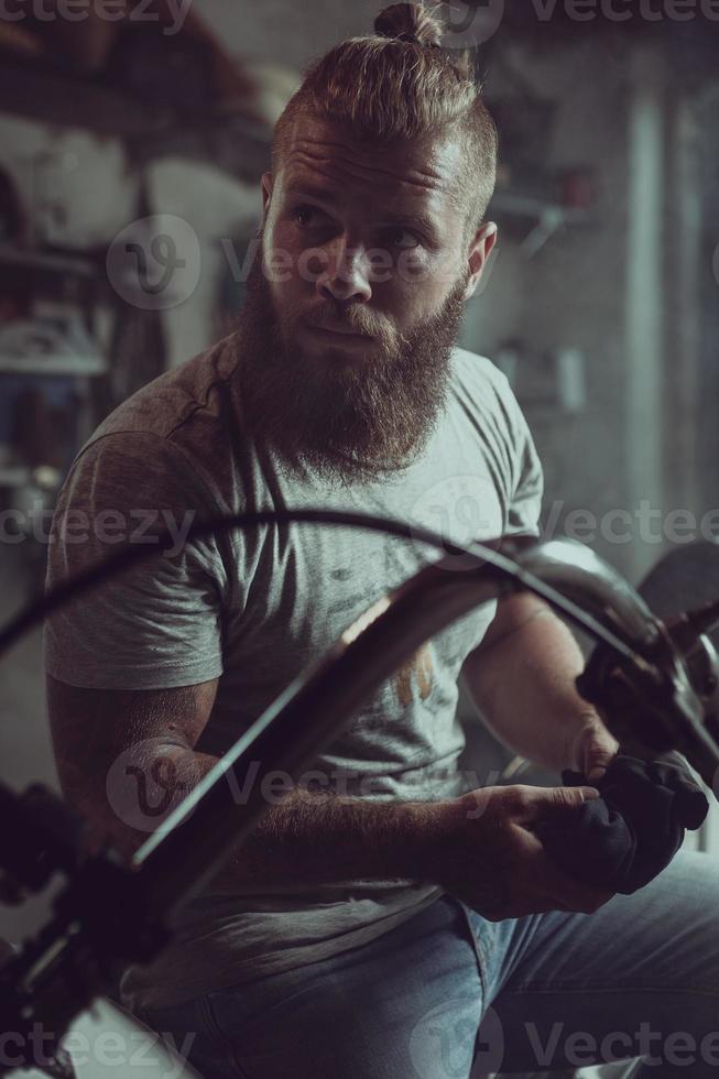 bell'uomo barbuto si siede su un sedile di motocicletta e distoglie lo sguardo foto