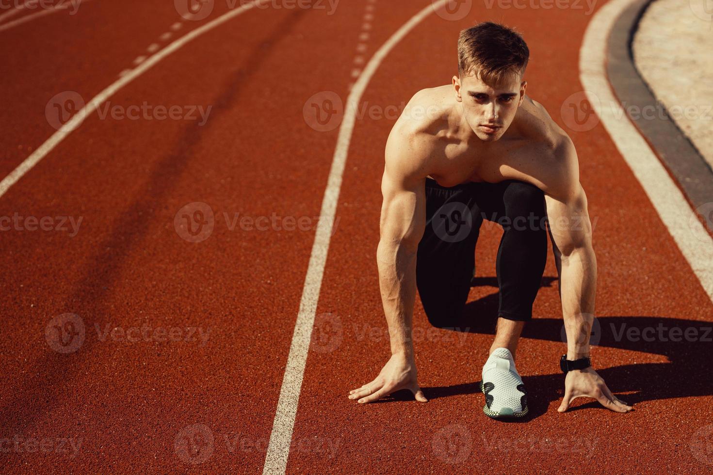 giovane ragazzo con un corpo atletico che si prepara a correre foto