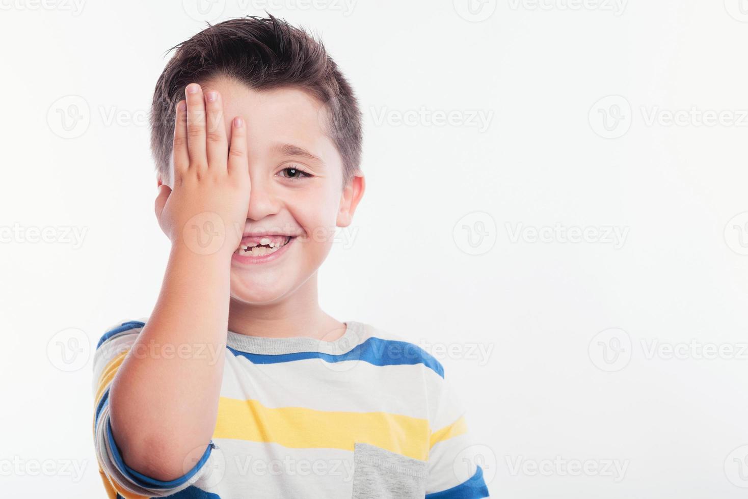 bambino sorridente che copre il suo occhio foto