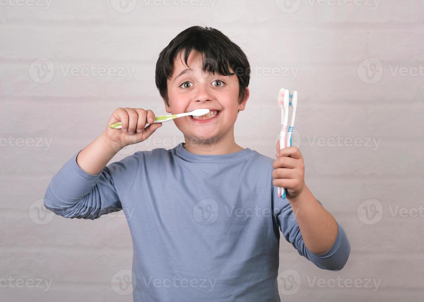 bambino felice che pulisce i denti con lo spazzolino da denti foto