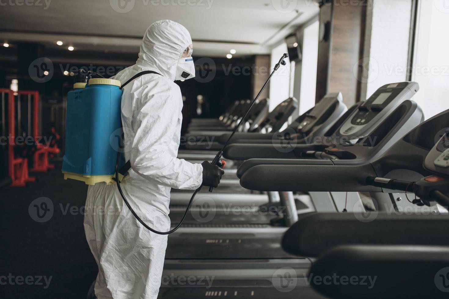 pulizia e disinfezione in luoghi affollati in mezzo all'epidemia di coronavirus pulizia e disinfezione palestra prevenzione delle infezioni e controllo dell'epidemia. tuta protettiva e maschera e borsa spray foto