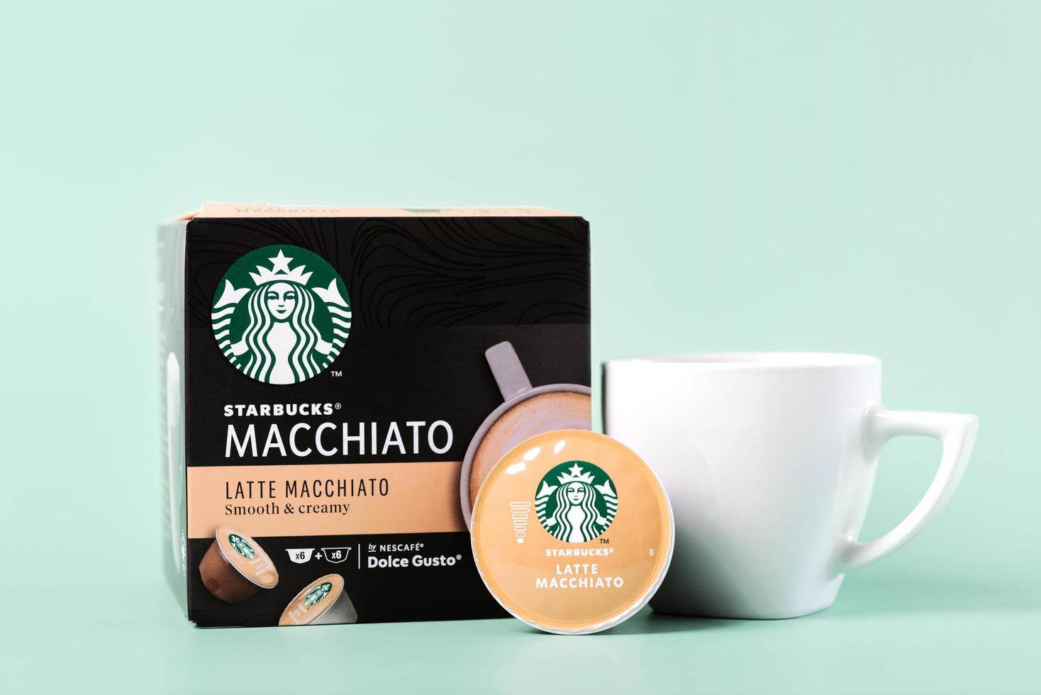 scatola di capsule di caffè latte macchiato starbucks accanto a una tazza di caffè bianca e capsule latte macchiato foto