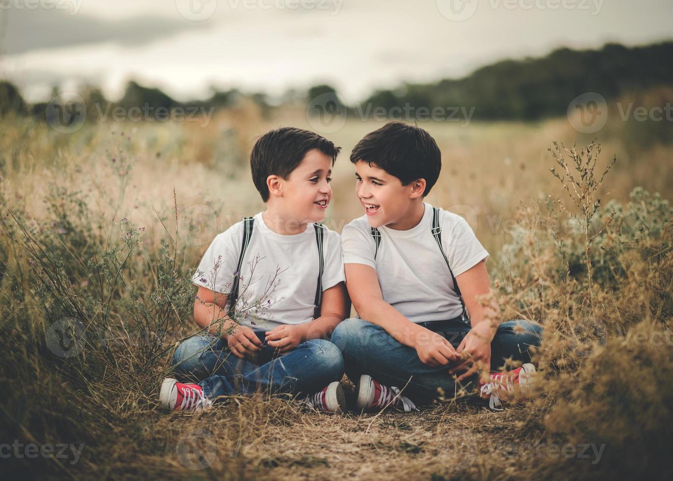 fratelli sorridenti seduti nel campo foto