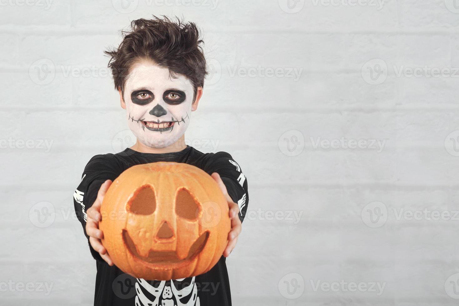 felice halloween.bambino divertente in un costume da scheletro con zucca di halloween foto