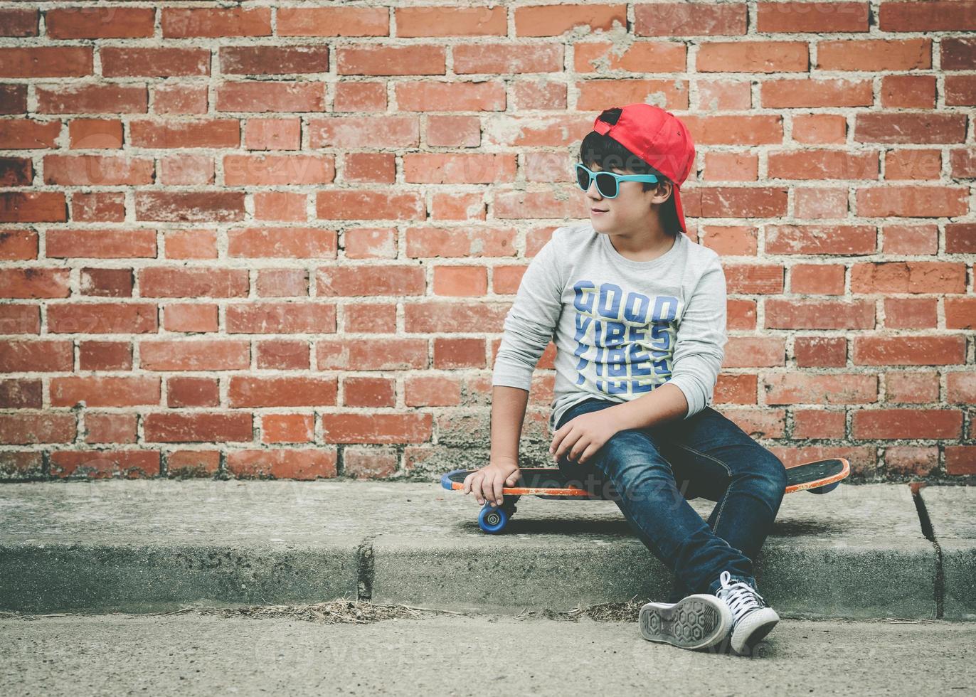 bambino con skateboard e occhiali da sole foto
