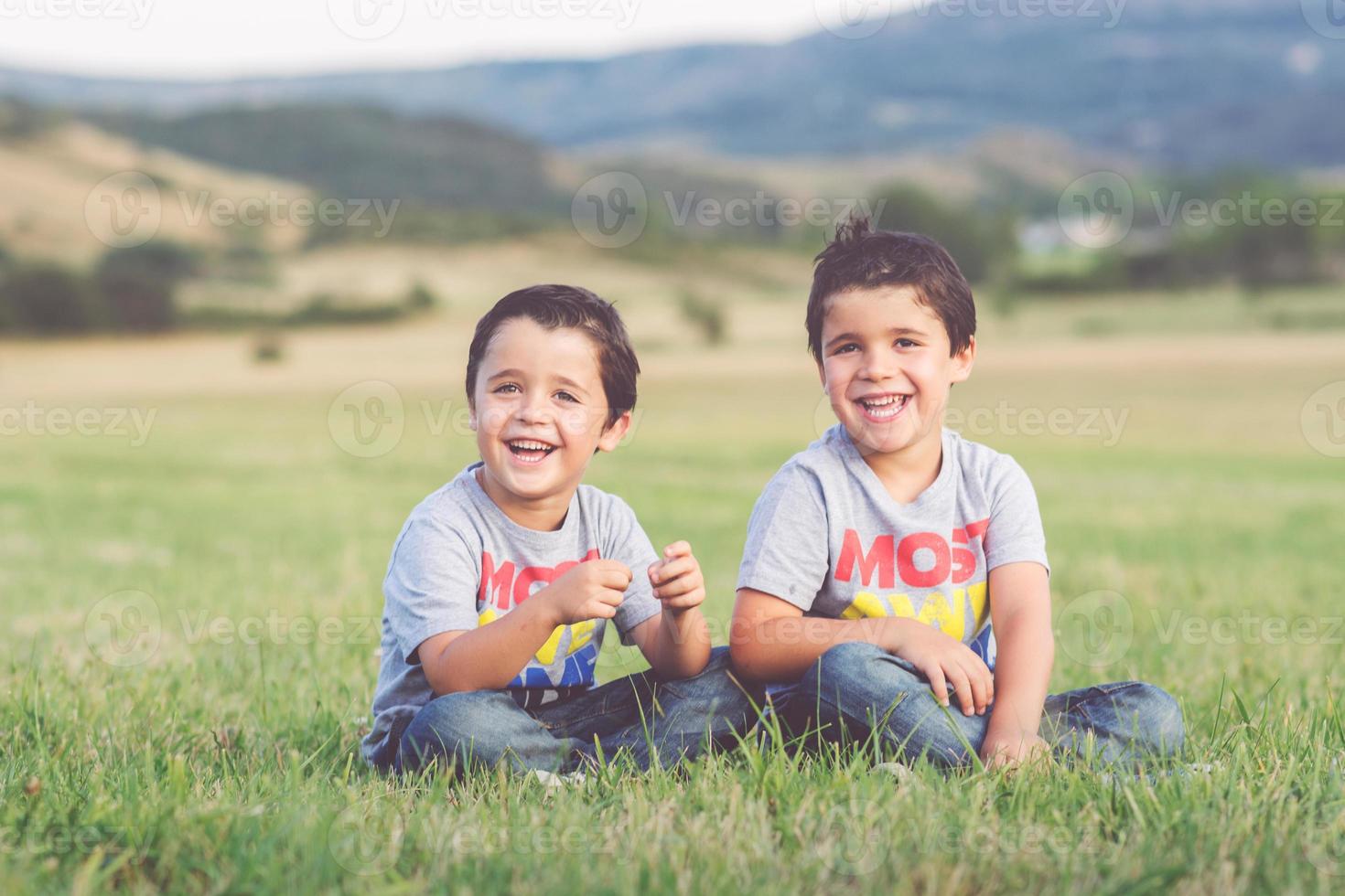 fratelli sorridenti seduti nel campo foto