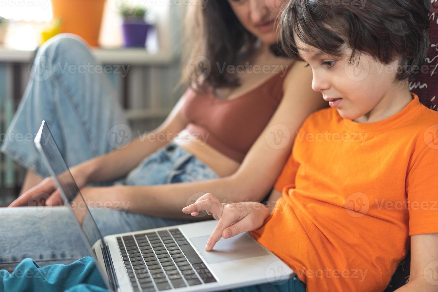 una donna con un bambino è seduta davanti a un laptop foto