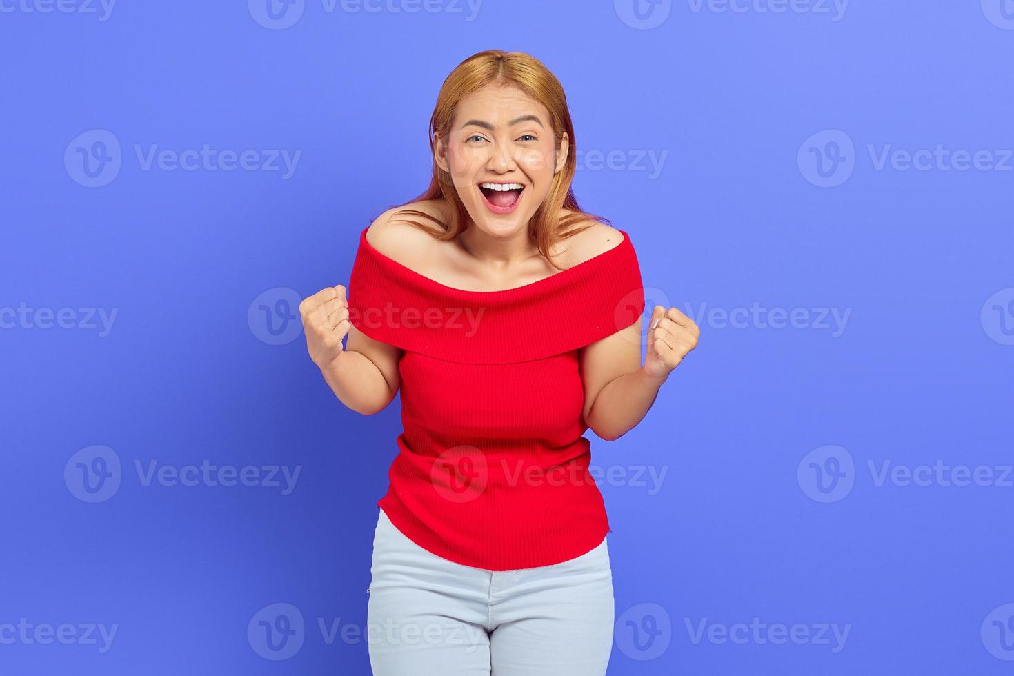 ritratto di giovane donna asiatica eccitata che celebra la vittoria isolata su sfondo viola foto