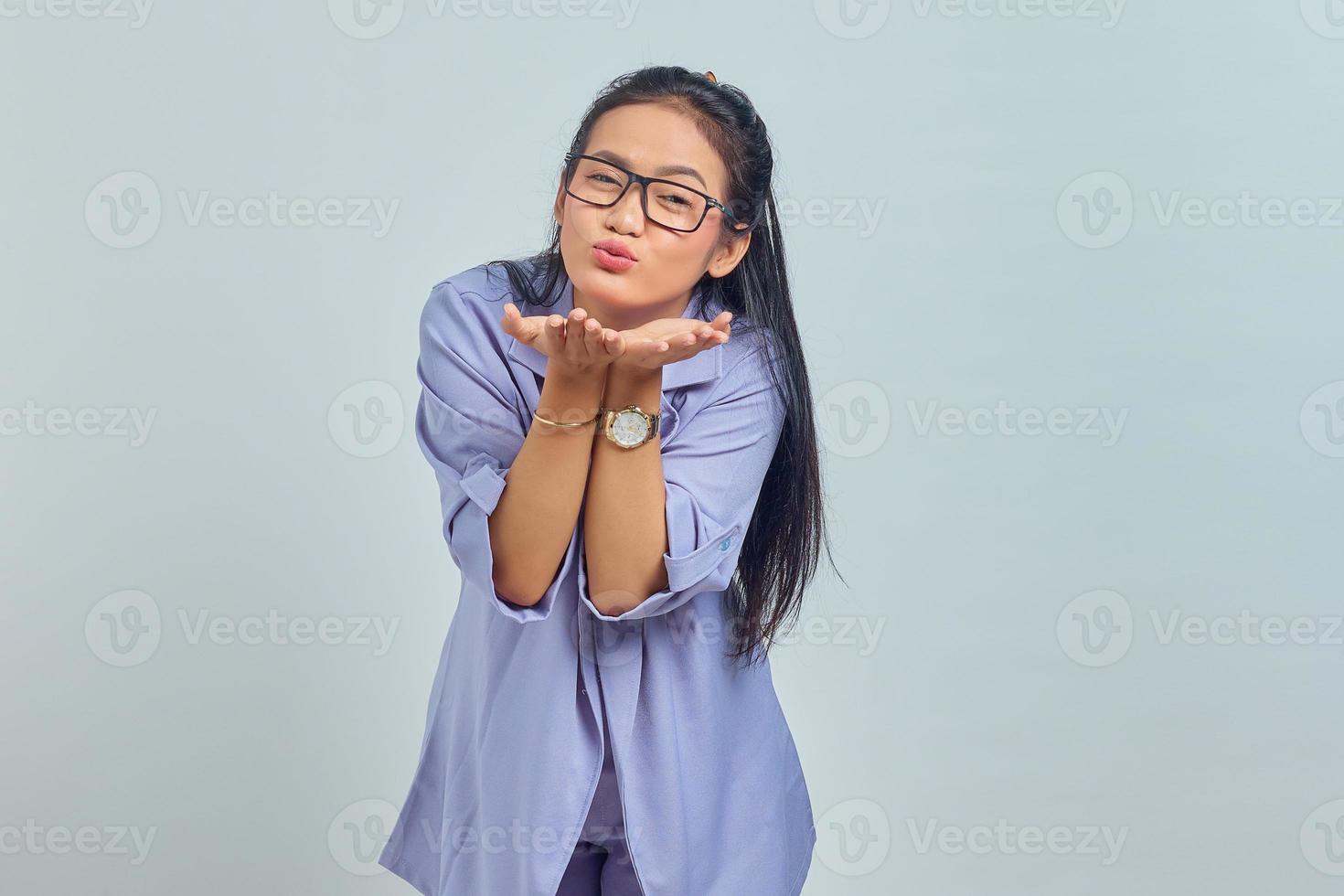 ritratto di affascinante giovane donna asiatica tenere i palmi della mano inviare un bacio d'aria al fidanzato su sfondo bianco foto