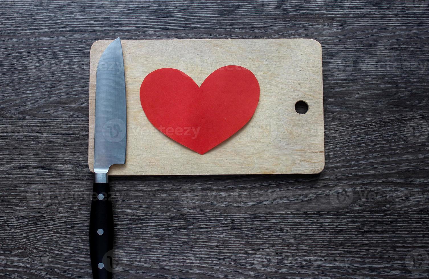 coltello con un cuore di carta su un tagliere foto