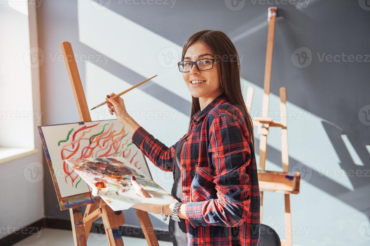 artista ragazza piuttosto carina dipinge su tela dipinto sul cavalletto. foto