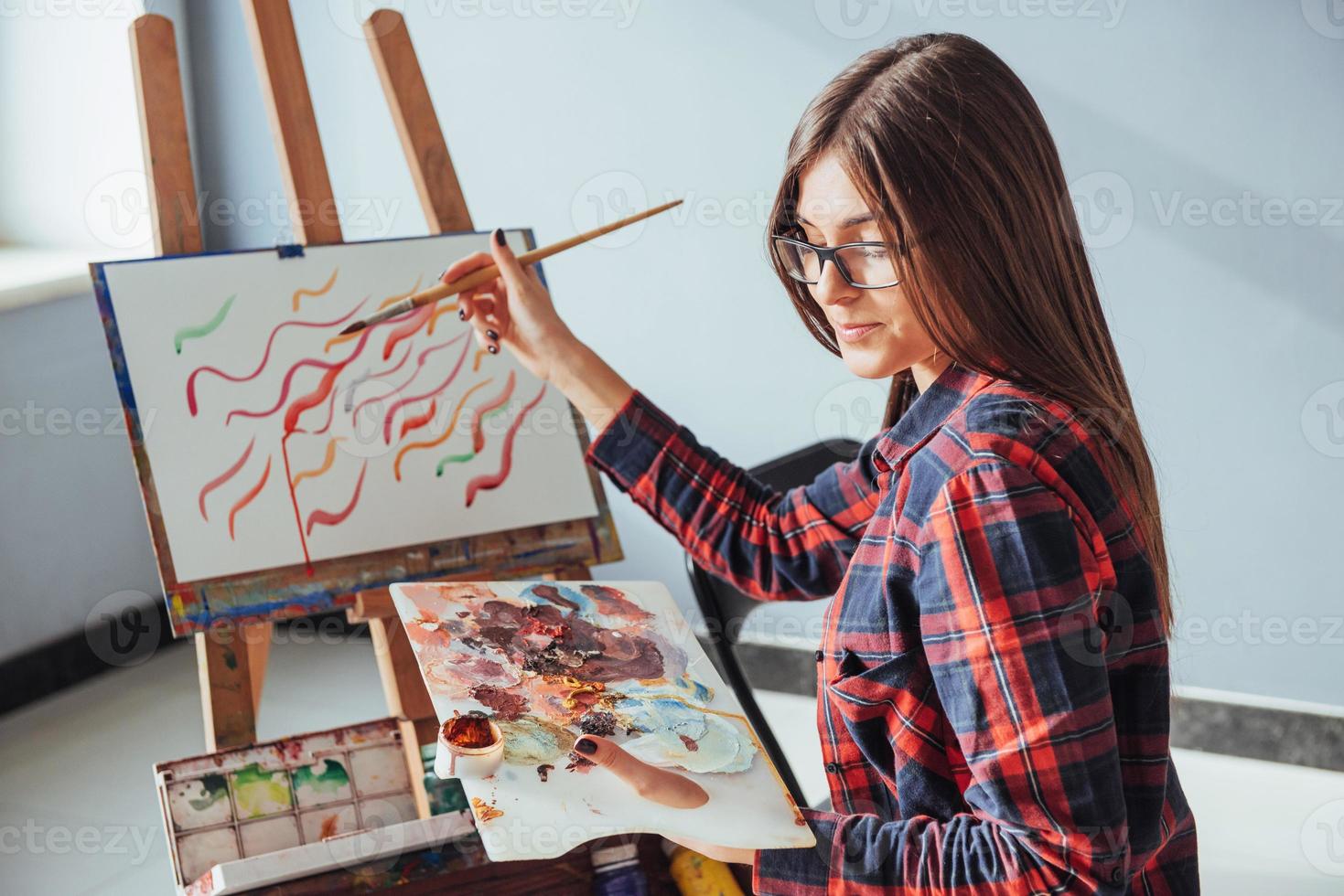 artista ragazza piuttosto carina dipinge su tela dipinto sul cavalletto. foto