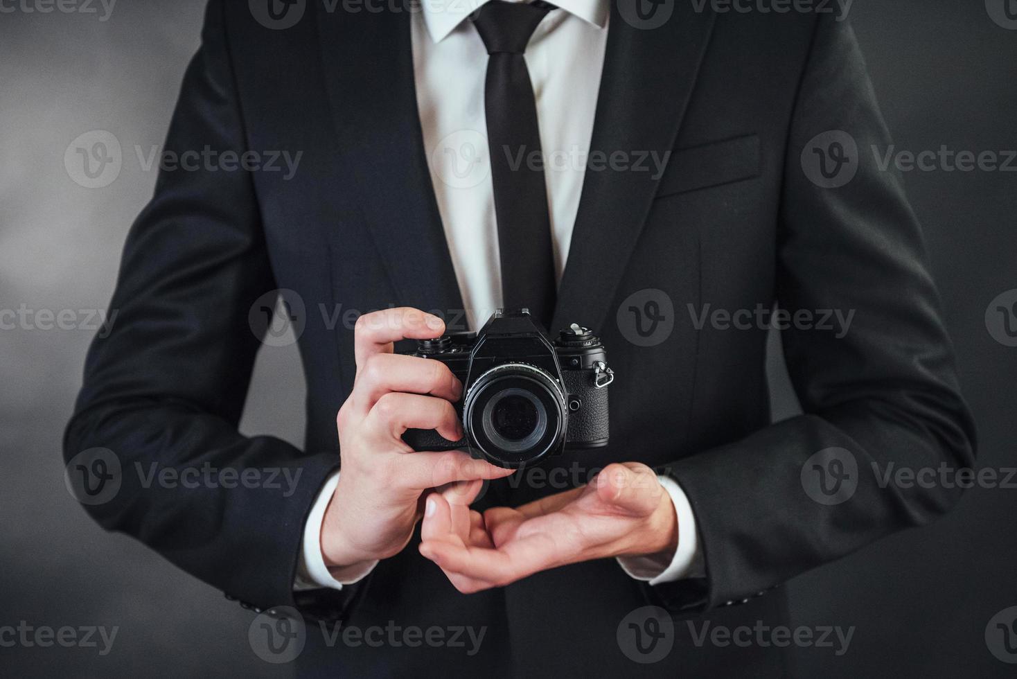 uomo che tiene la fotocamera digitale nera. Nello studio foto