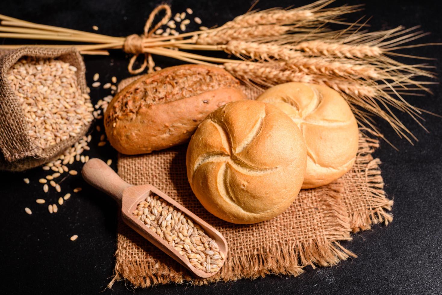 bel pane appena sfornato con chicchi di grano su uno sfondo di cemento scuro foto