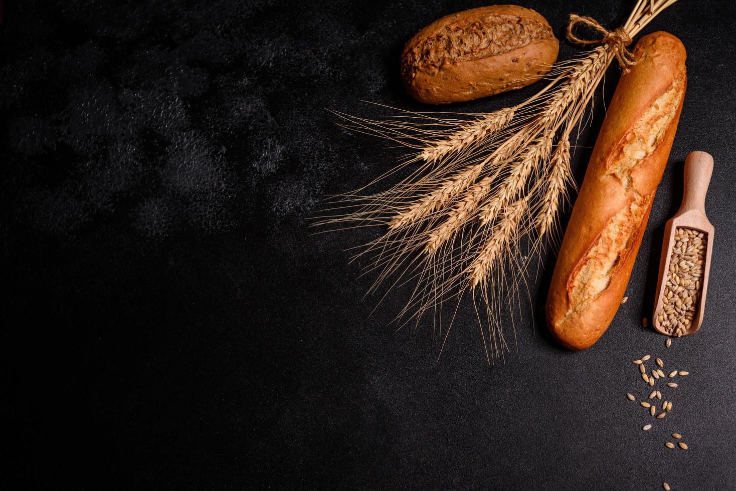 bel pane appena sfornato con chicchi di grano su uno sfondo di cemento scuro foto