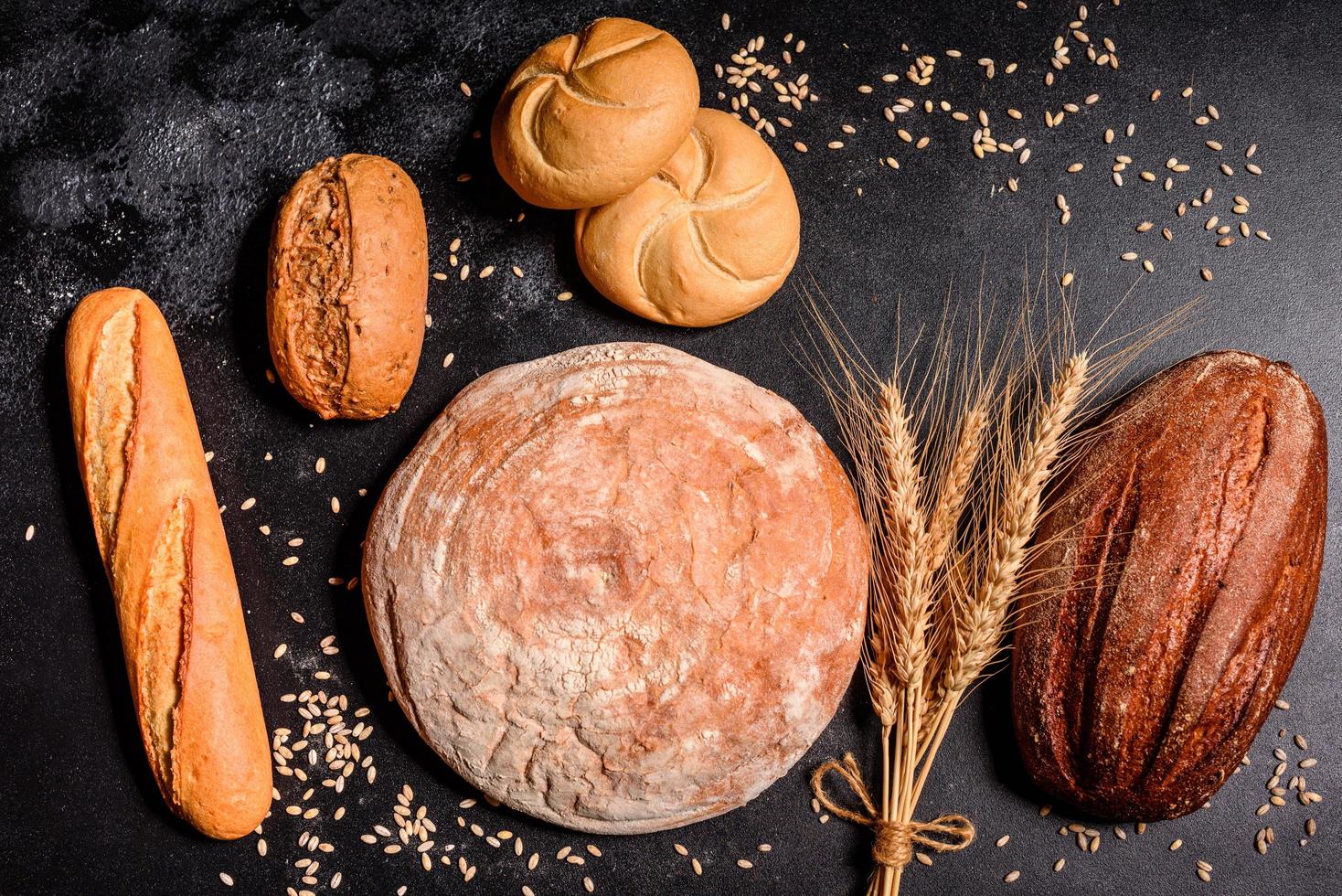 bel pane appena sfornato con chicchi di grano su uno sfondo di cemento scuro foto