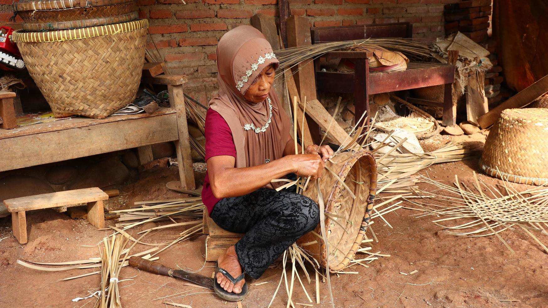 Artigiana di cestini di bambù mentre fa il suo lavoro in un luogo, batang, jawa tengah, indonesia, 26 maggio 2019 foto