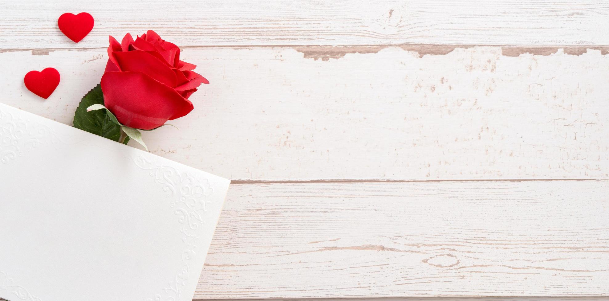 concetto di saluto - belle rose e cuori a forma di scheda vuota bianca isolata su un tavolo di legno luminoso, spazio per la copia, disposizione piatta, vista dall'alto, mock up foto
