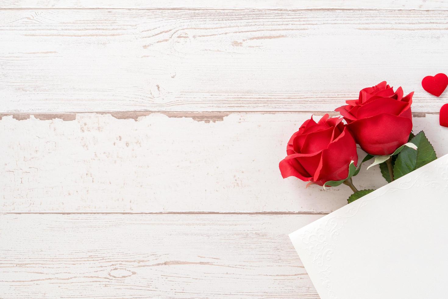 concetto di saluto - belle rose e cuori a forma di scheda vuota bianca isolata su un tavolo di legno luminoso, spazio per la copia, disposizione piatta, vista dall'alto, mock up foto