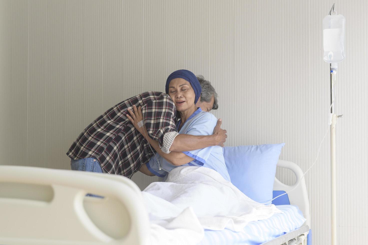 uomo anziano che visita una donna malata di cancro che indossa una sciarpa per la testa in ospedale, assistenza sanitaria e concetto medico foto