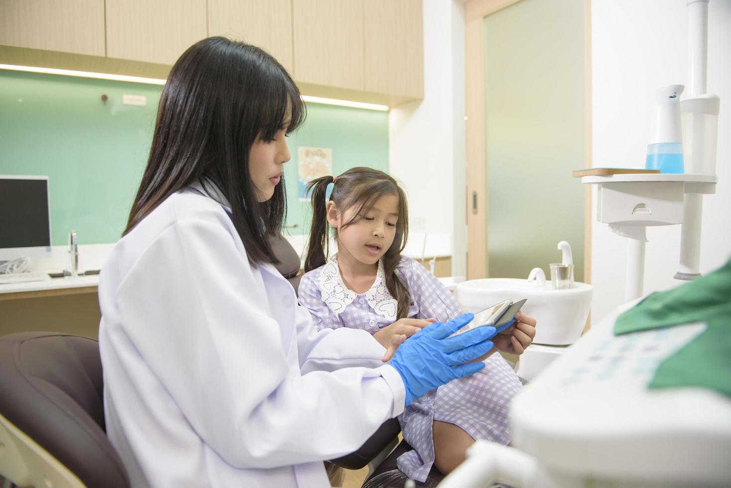 dentista femminile che spiega i raggi x dei denti a una bambina in clinica dentale, controllo dei denti e concetto di denti sani foto