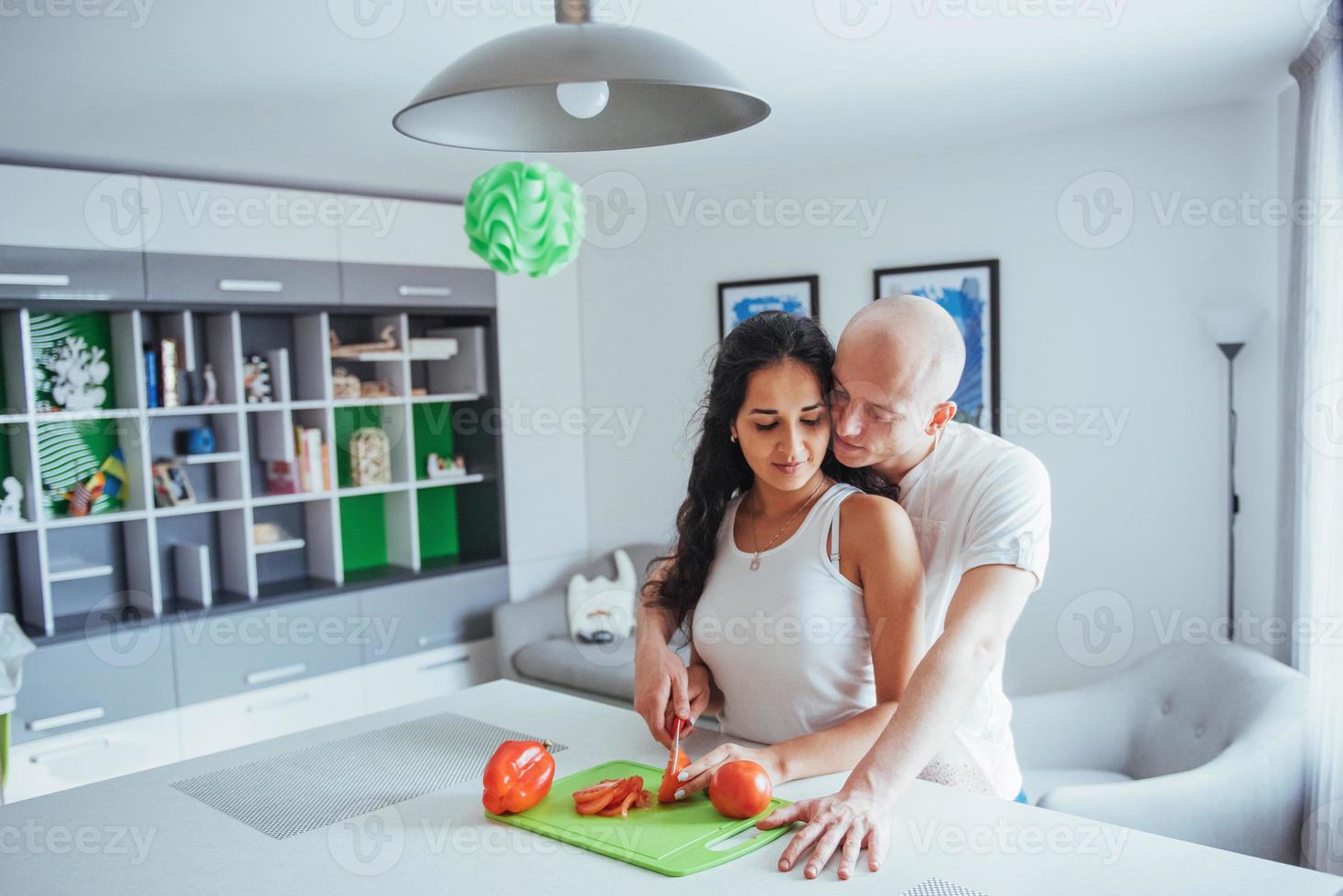 bella giovane coppia macina insieme le verdure in cucina. foto