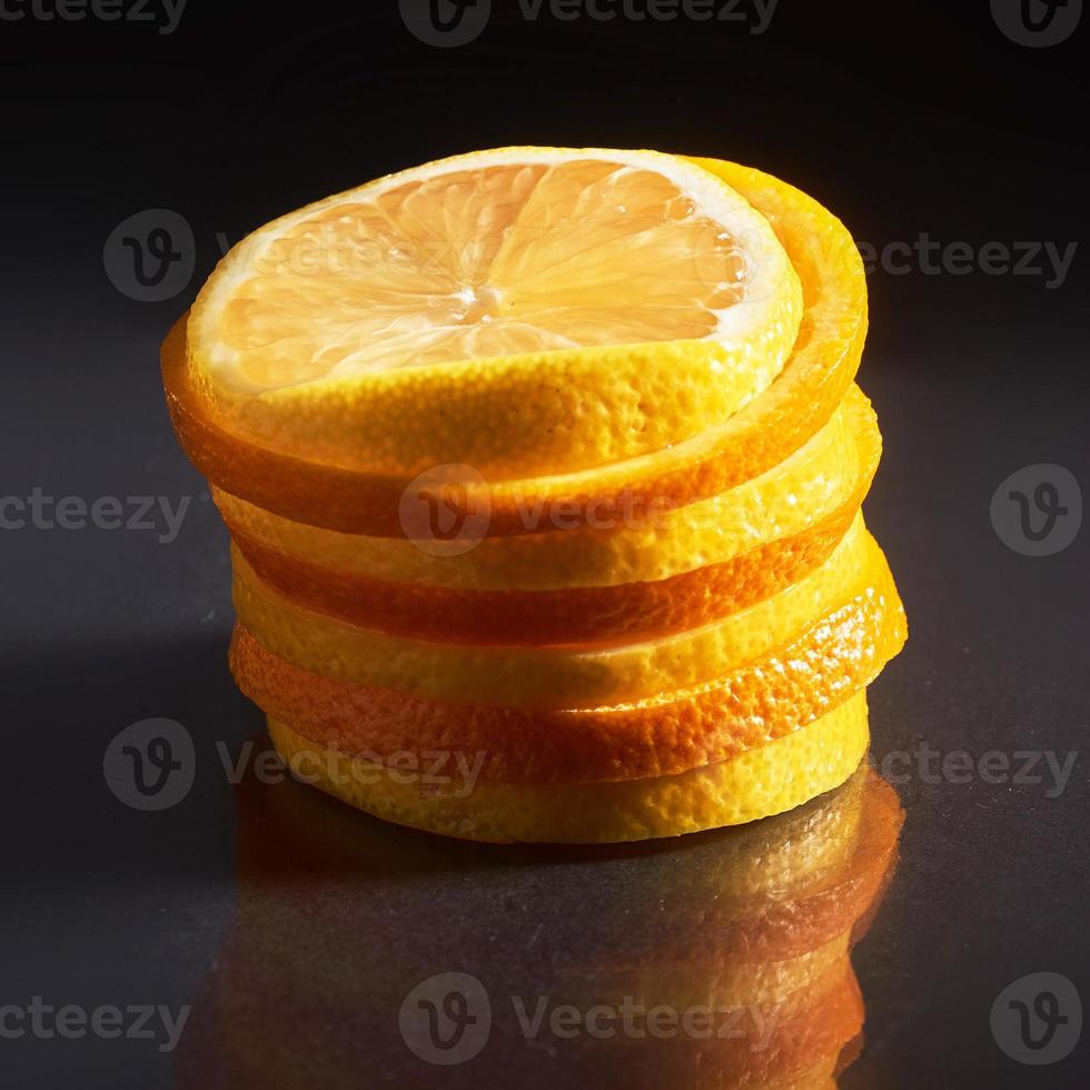 una pila di arancia e limone freschi isolati su sfondo nero foto