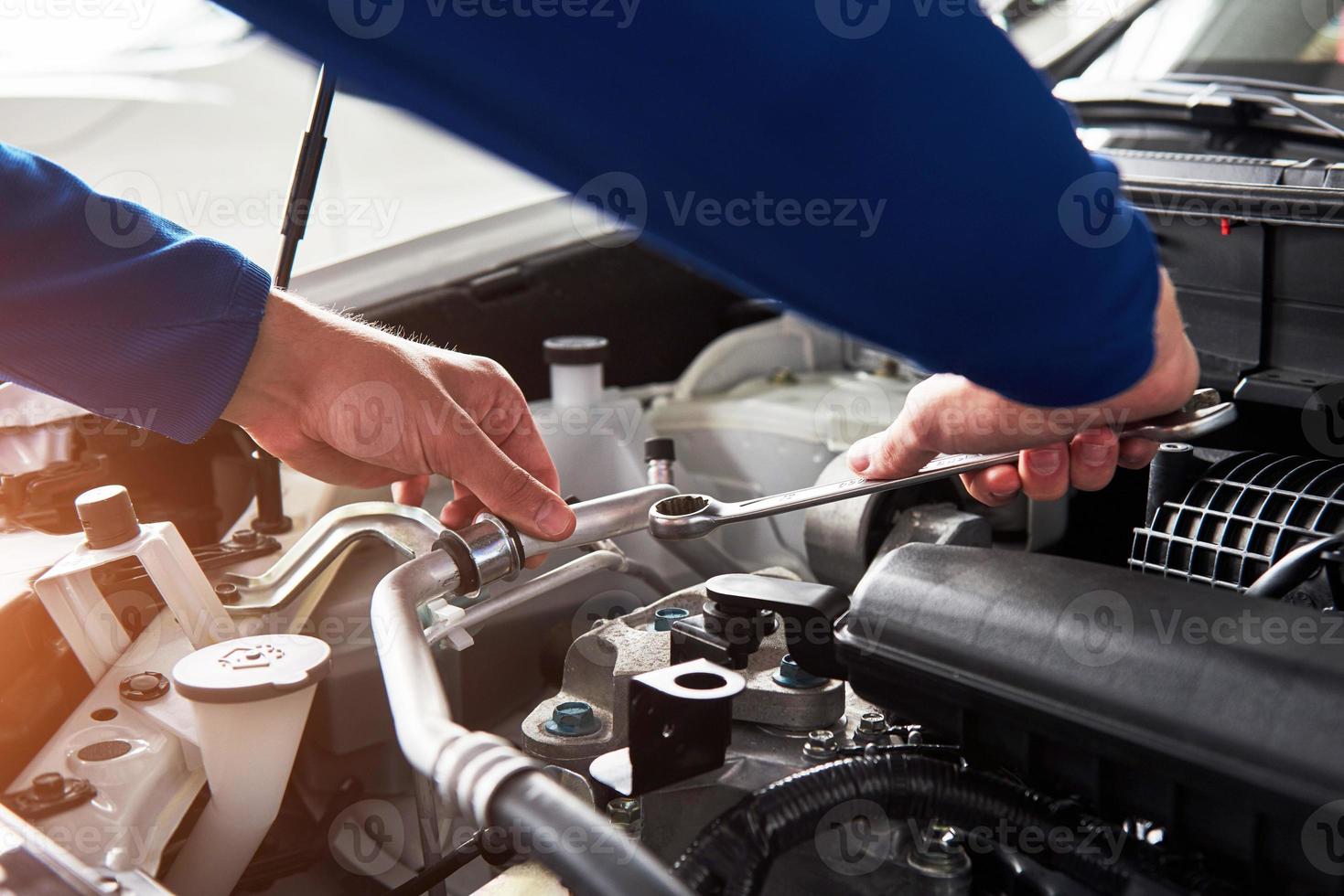 mani del meccanico di automobili con una chiave inglese in garage foto