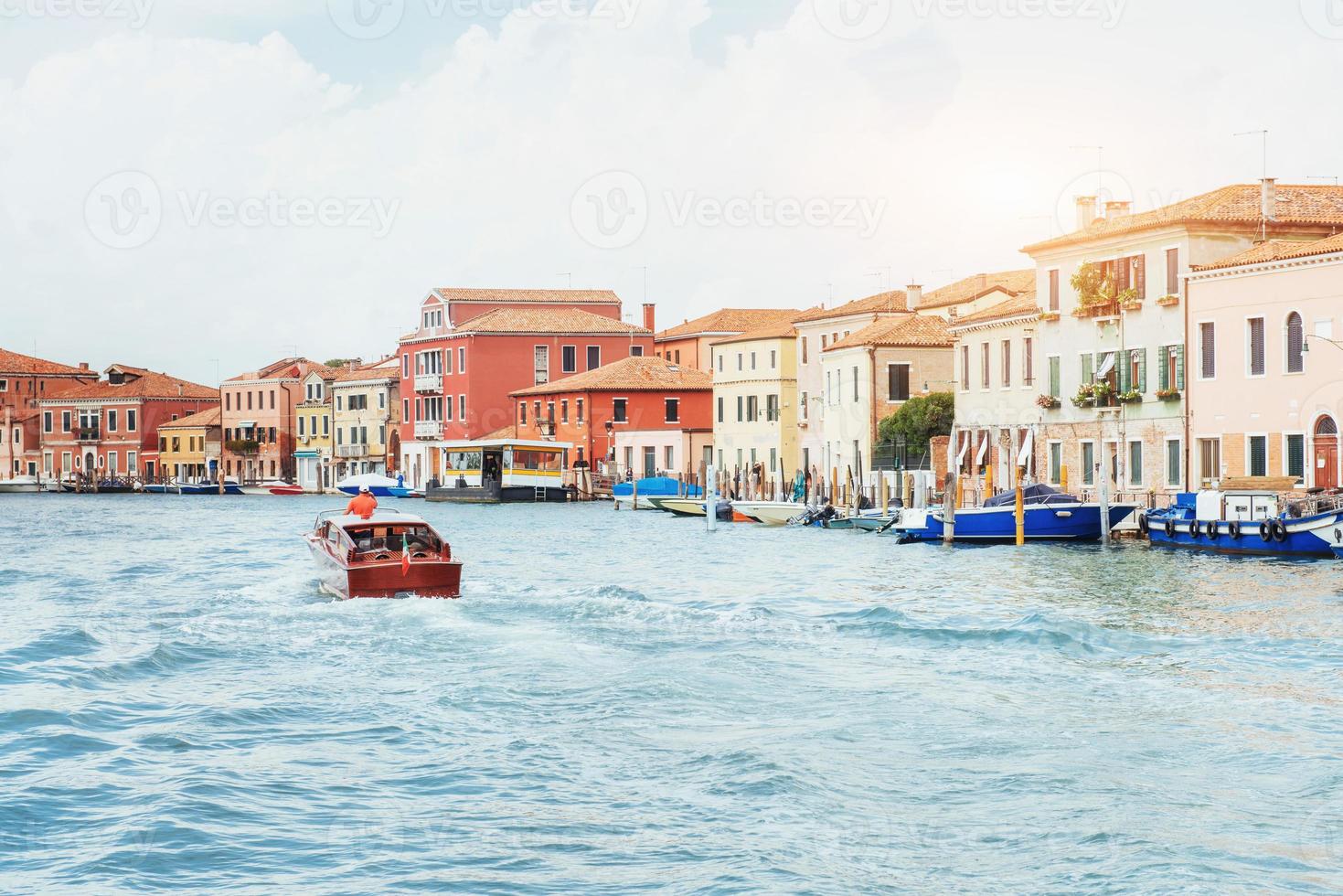 canale d'acqua verde con gondole e facciate colorate di vecchi edifici medievali al sole a venezia, italia. foto