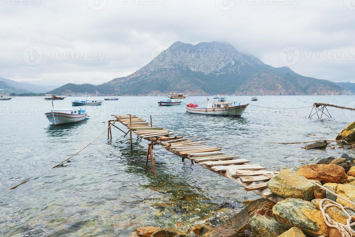 barche vicino al molo rotto, immergendo un mare blu calmo e tranquillo foto