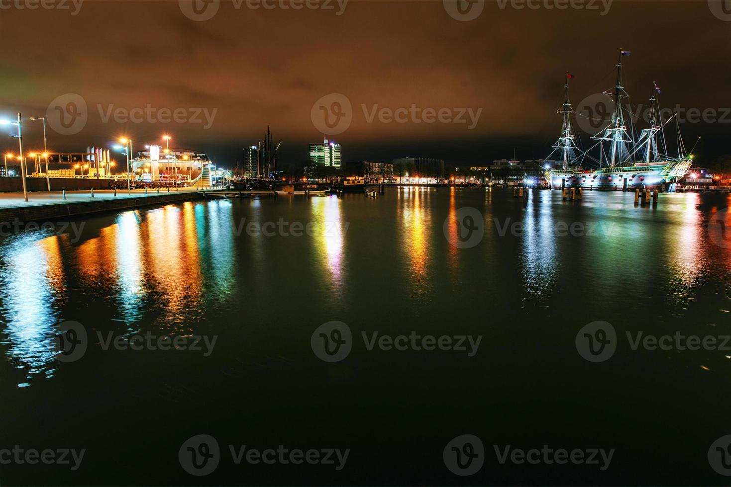 illuminazione notturna di edifici e barche vicino all'acqua nel canale. foto