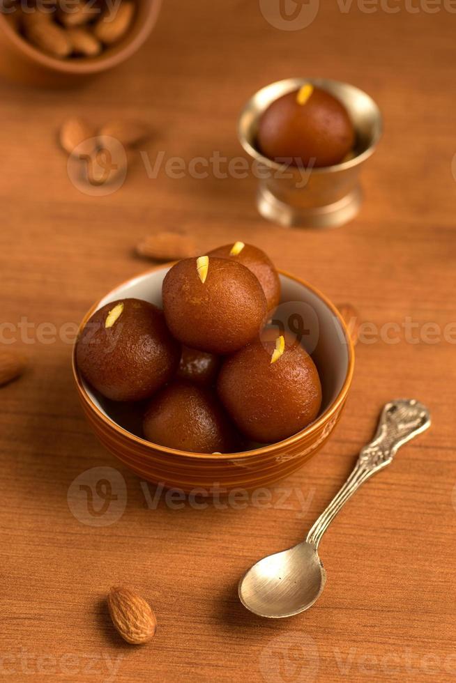 gulab jamun in ciotola e ciotola antica in rame con cucchiaio. dessert indiano o piatto dolce. foto