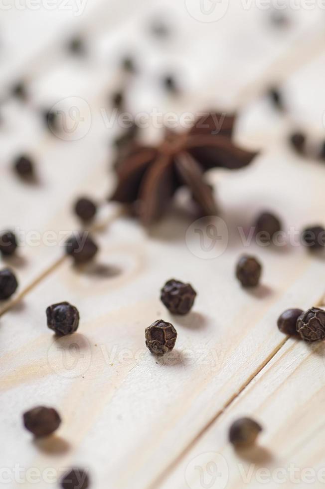 spezie ed erbe aromatiche. cibo e ingredienti della cucina. stelle di anice e grani di pepe nero su uno sfondo di legno. foto