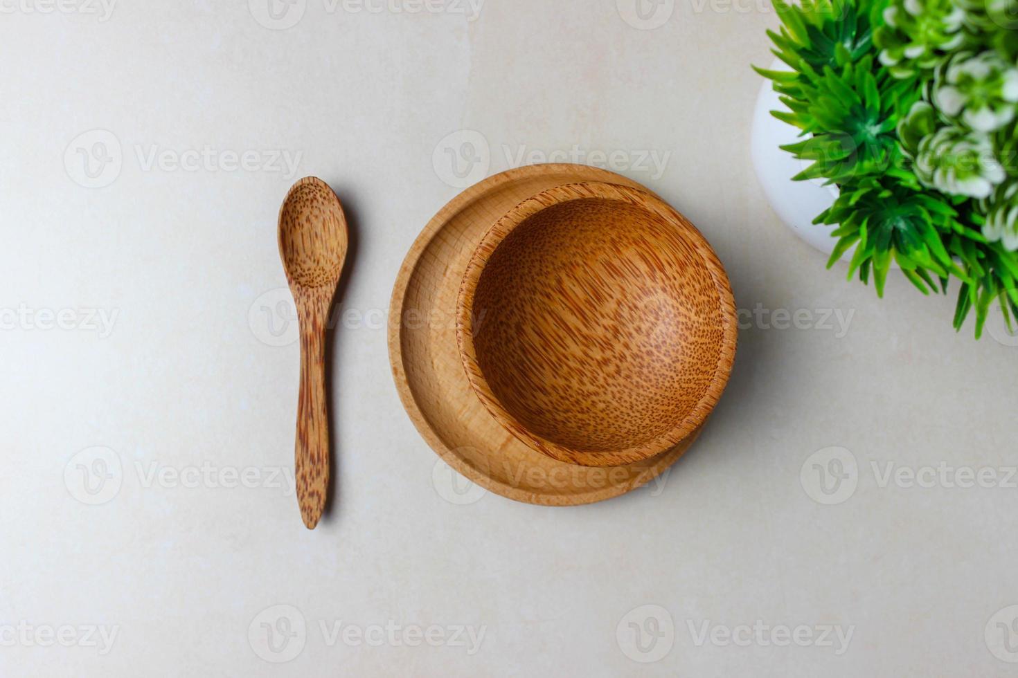 utensili in legno sul tavolo della cucina. piatto tondo, un cucchiaio, una pianta verde. il concetto di servire, cucinare, cucinare, dettagli interni. vista dall'alto foto