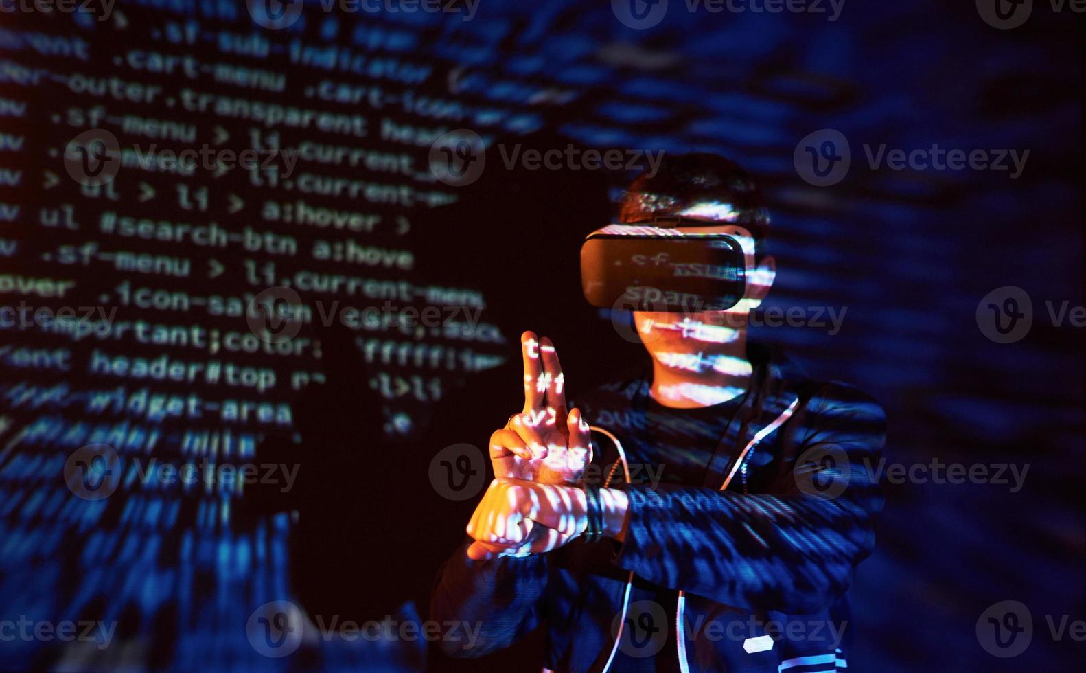 attacco informatico con hacker incappucciato irriconoscibile che utilizza la realtà virtuale, effetto glitch digitale foto