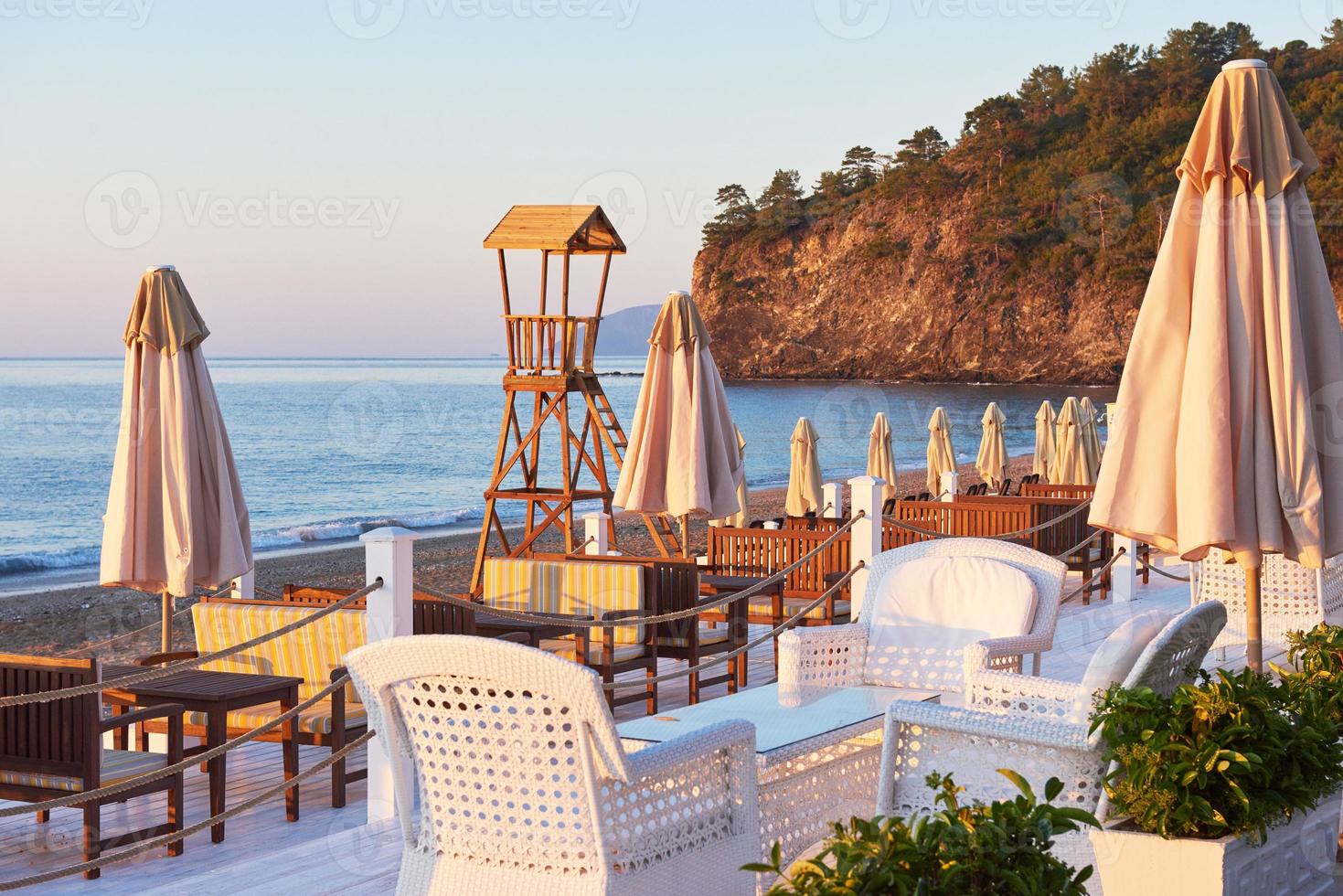 vista panoramica della spiaggia sabbiosa privata con lettini e parasokamy sul mare e sulle montagne. ricorrere. foto