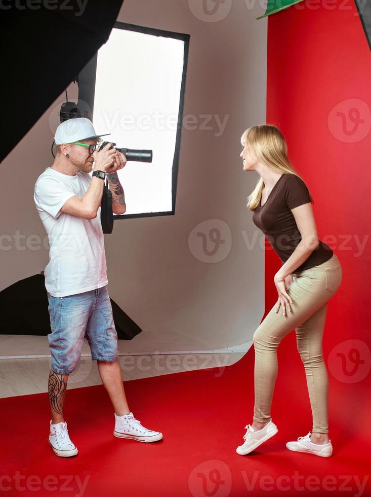 modello in posa per il fotografo in studio su sfondo rosso. concetto professionale, di istruzione, di tecnologia foto