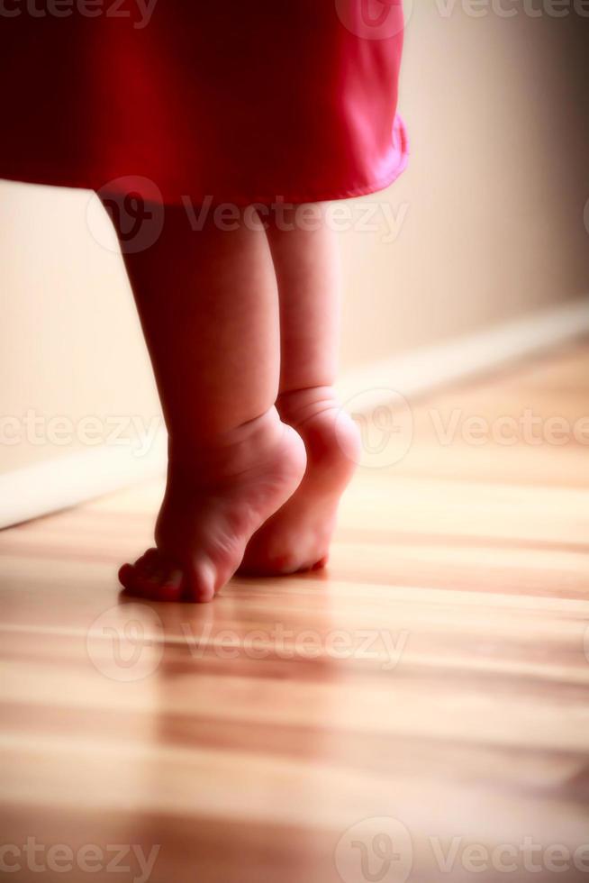 piedi del bambino che si allungano sul pavimento di legno foto